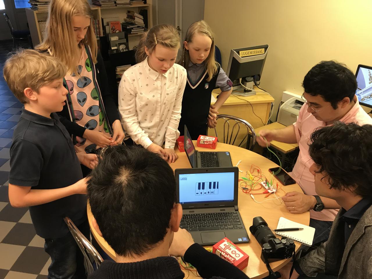 A group of students play with wires connected to laptops