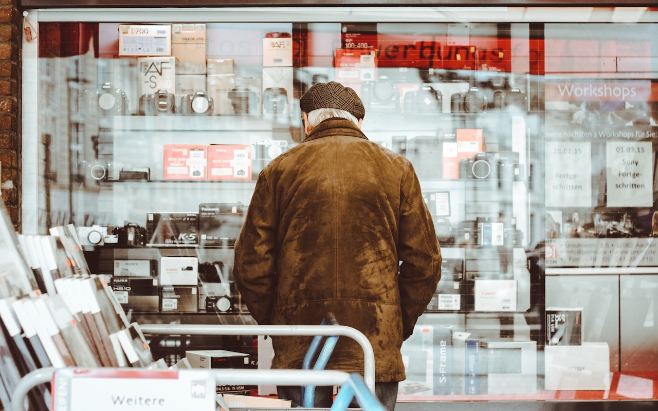 Old man looking at a display of cameras